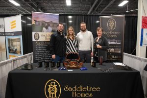 4 people standing behind saddletree homes booth