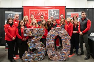 18 members of the classic homes team standing for a 30 year anniversary picture.