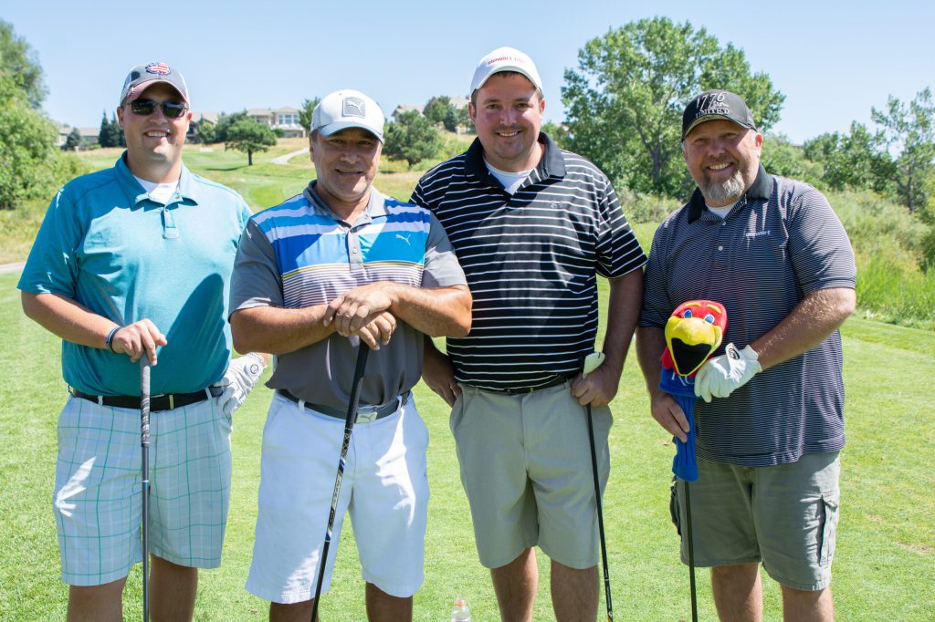 4 people posing for a picture on a golf course