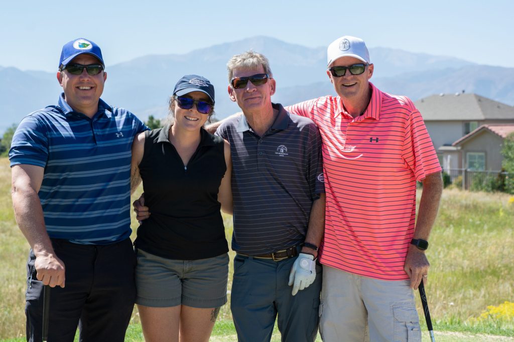 4 people posing for a picture on a golf course