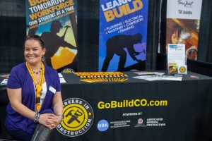 One person smiling in front of their booth at an event