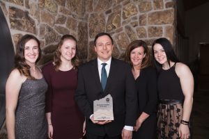 5 people posing for a photo one with an award