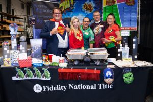 Five people dressed in super hero themes at their booth at an event