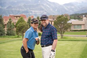 2 people including john suthers posing for a picture on a golf course